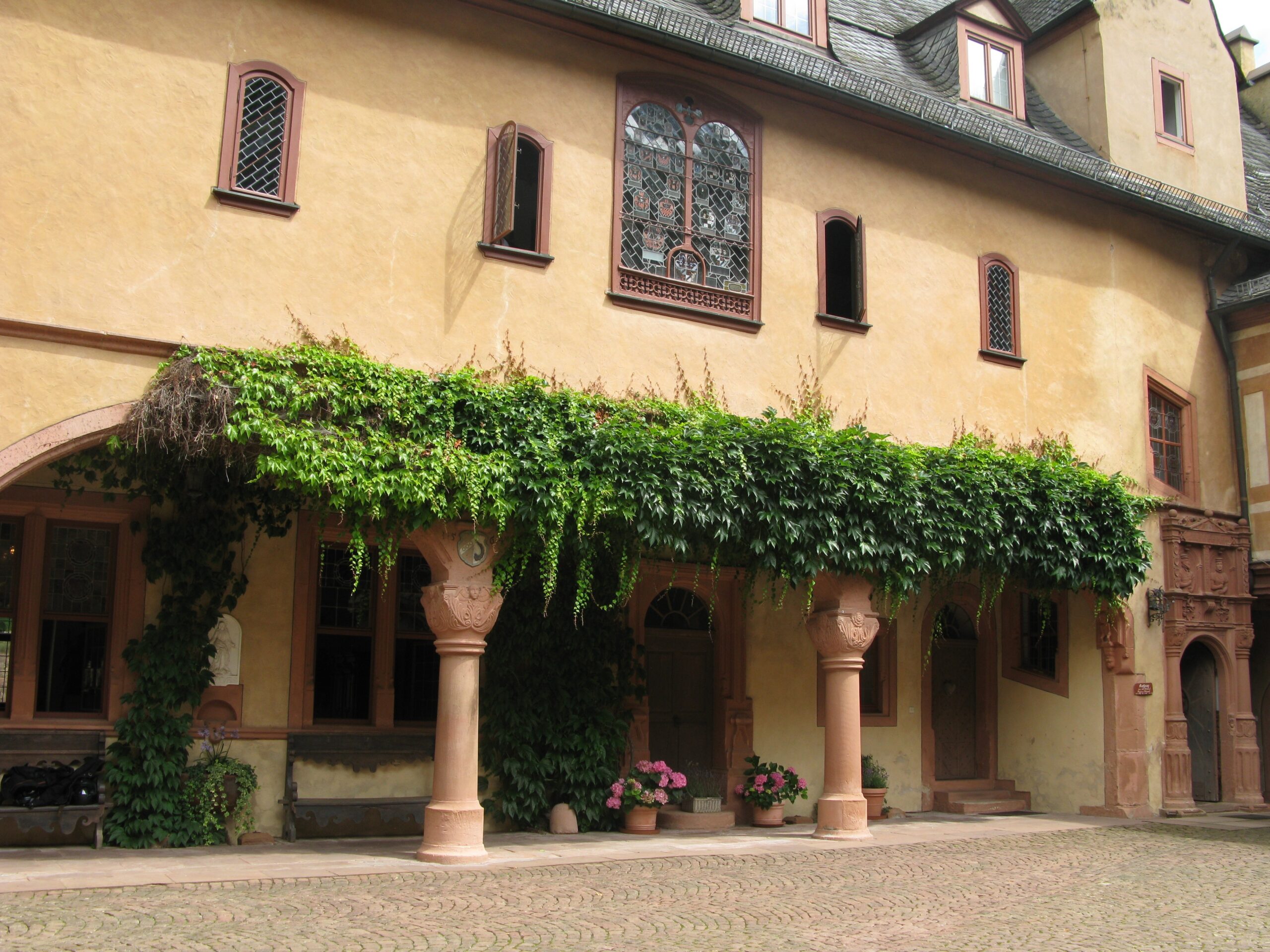 Arkade eines älteren Gebäudes mit grün bewachsener Überdachung